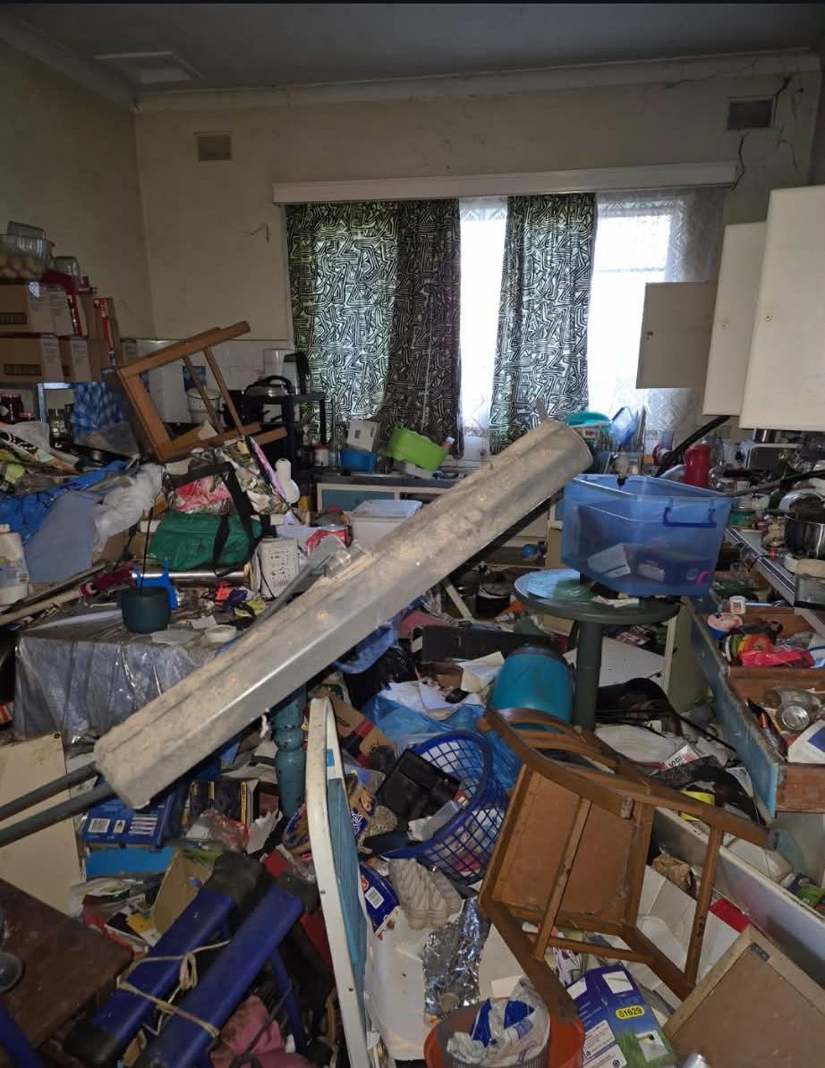 A kitchen and living space overwhelmed by hoarded belongings